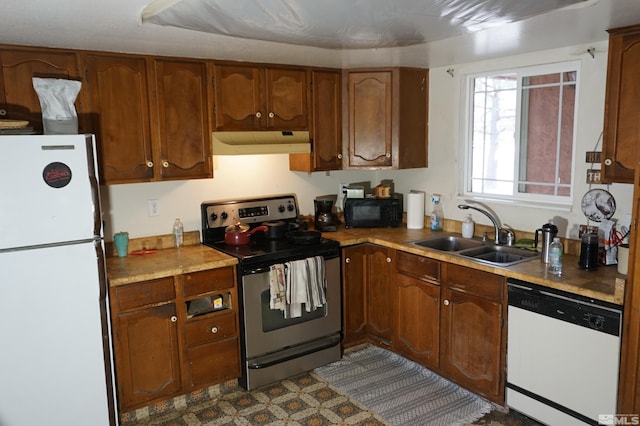 kitchen with light countertops, brown cabinetry, a sink, white appliances, and under cabinet range hood