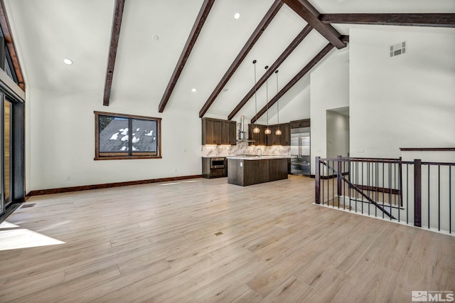 living area featuring high vaulted ceiling, light wood finished floors, beamed ceiling, and visible vents