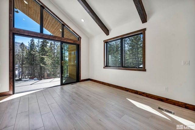 empty room with light wood-style flooring, beamed ceiling, a wealth of natural light, and baseboards