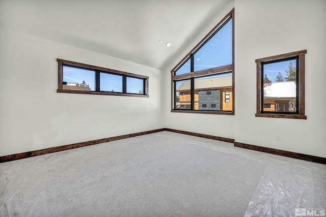 empty room with high vaulted ceiling and baseboards