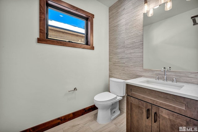 bathroom featuring baseboards, vanity, and toilet