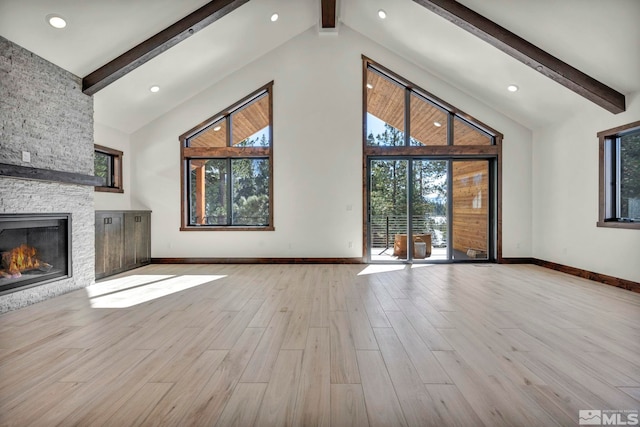 unfurnished living room with baseboards, a stone fireplace, light wood-style floors, high vaulted ceiling, and beam ceiling