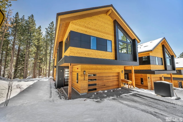 snow covered rear of property with an attached garage