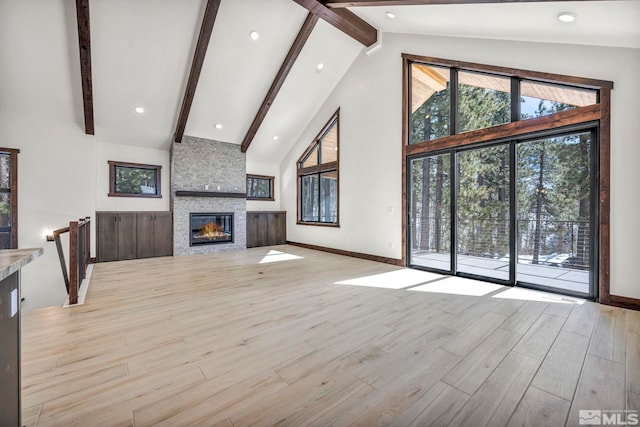 unfurnished living room with high vaulted ceiling, a fireplace, baseboards, light wood-style floors, and beamed ceiling