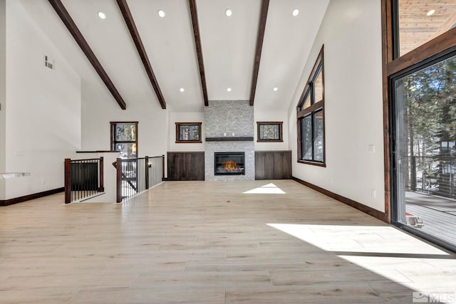 unfurnished living room with light wood-type flooring, high vaulted ceiling, a wealth of natural light, and beamed ceiling