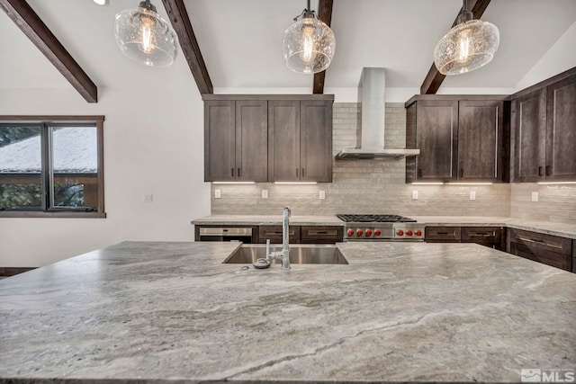 kitchen with wall chimney exhaust hood, light stone counters, hanging light fixtures, and a sink