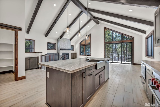 kitchen with a barn door, a center island with sink, decorative light fixtures, light countertops, and a sink