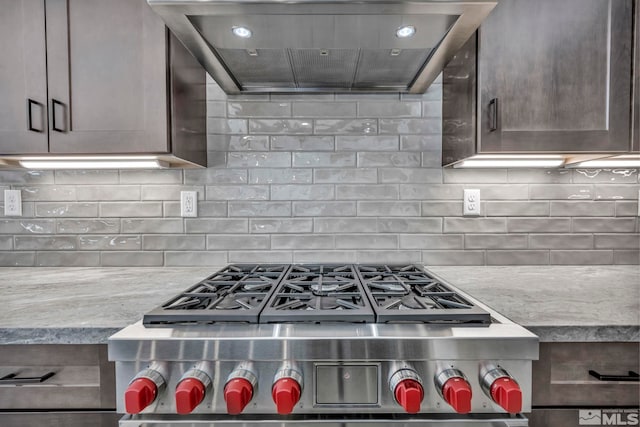 kitchen with dark brown cabinetry, light stone countertops, wall chimney range hood, high end stainless steel range oven, and decorative backsplash