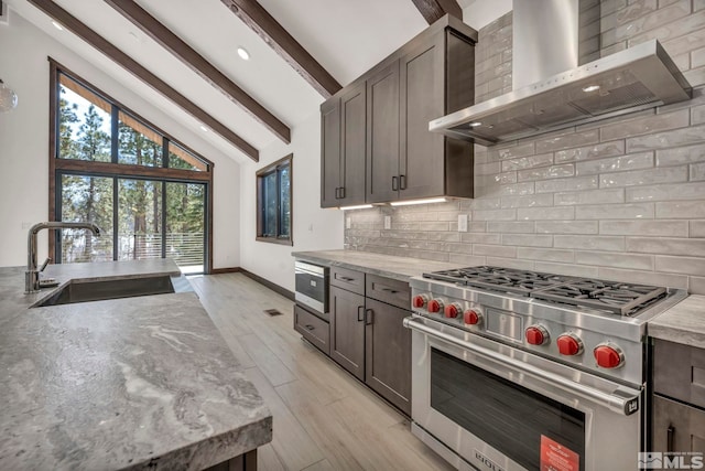 kitchen featuring decorative backsplash, wall chimney exhaust hood, beamed ceiling, stainless steel appliances, and a sink