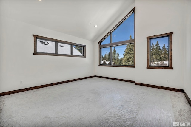 empty room featuring lofted ceiling, light carpet, and baseboards