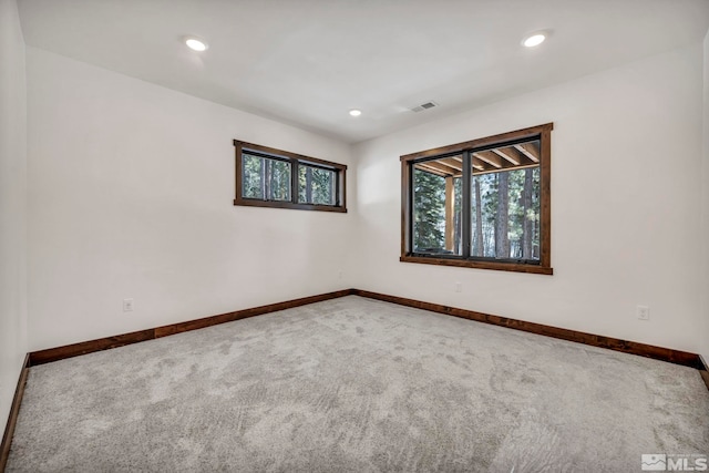 carpeted empty room featuring recessed lighting, visible vents, and baseboards