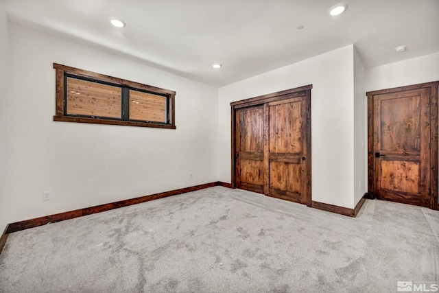 unfurnished bedroom with recessed lighting, a closet, light carpet, and baseboards