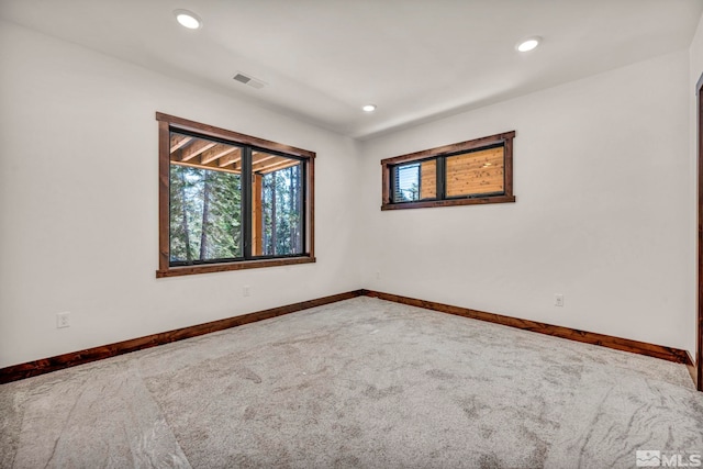 unfurnished room with carpet, visible vents, baseboards, and recessed lighting