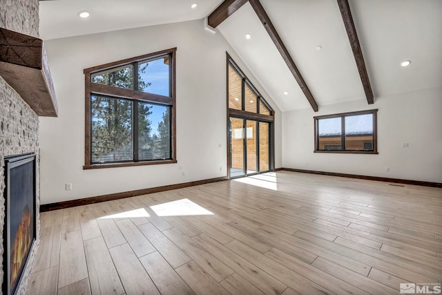 unfurnished living room with high vaulted ceiling, light wood-style flooring, a fireplace, baseboards, and beam ceiling