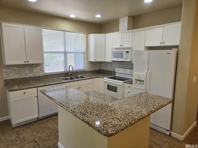 kitchen with white appliances, a sink, white cabinets, and a center island