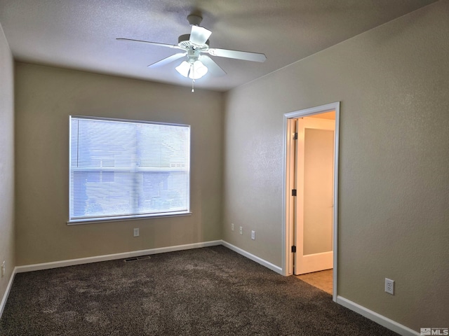 carpeted empty room with a ceiling fan and baseboards