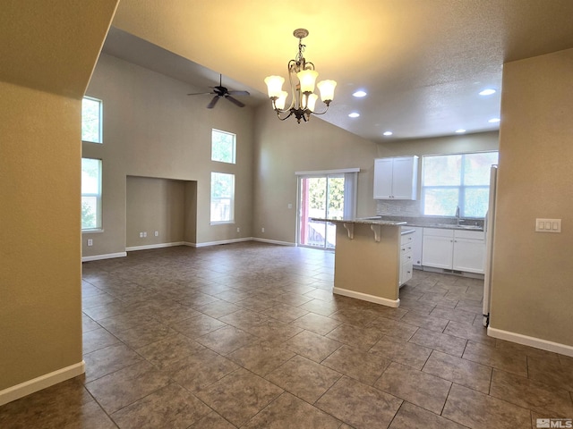 kitchen featuring a breakfast bar, decorative light fixtures, freestanding refrigerator, open floor plan, and white cabinetry