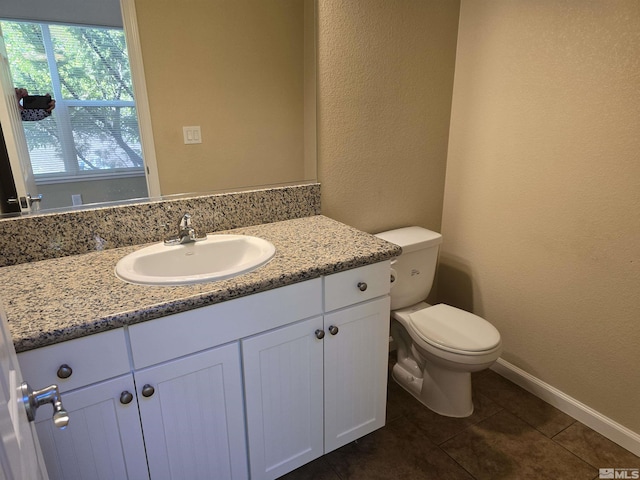 half bath with baseboards, a textured wall, toilet, tile patterned floors, and vanity