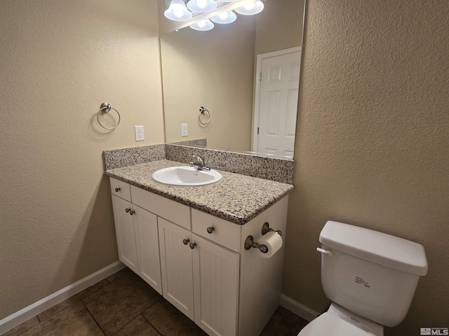 bathroom with toilet, tile patterned flooring, vanity, and baseboards