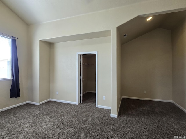 unfurnished room with dark carpet, baseboards, and vaulted ceiling