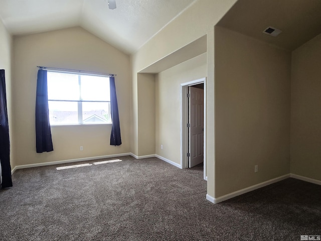 unfurnished room featuring baseboards, visible vents, dark carpet, and vaulted ceiling