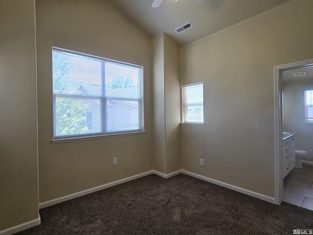 spare room featuring lofted ceiling, visible vents, dark carpet, ceiling fan, and baseboards