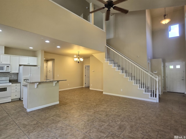 kitchen featuring white appliances, a kitchen island, decorative light fixtures, and white cabinets