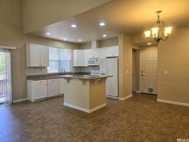 kitchen featuring a center island, pendant lighting, white cabinets, white appliances, and a kitchen bar