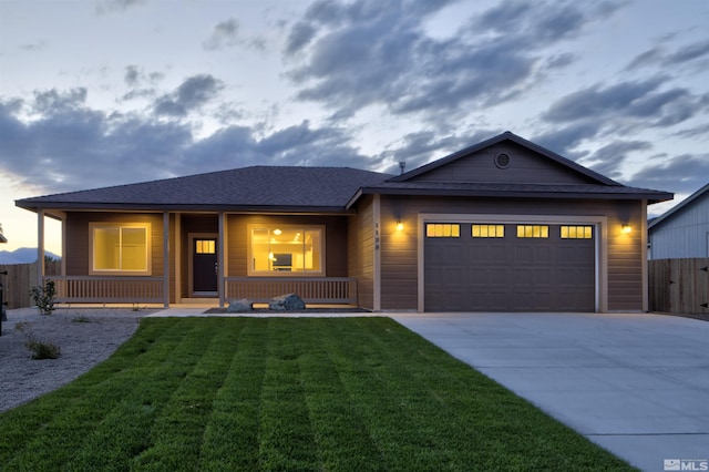 ranch-style house featuring fence, a porch, concrete driveway, a garage, and a lawn