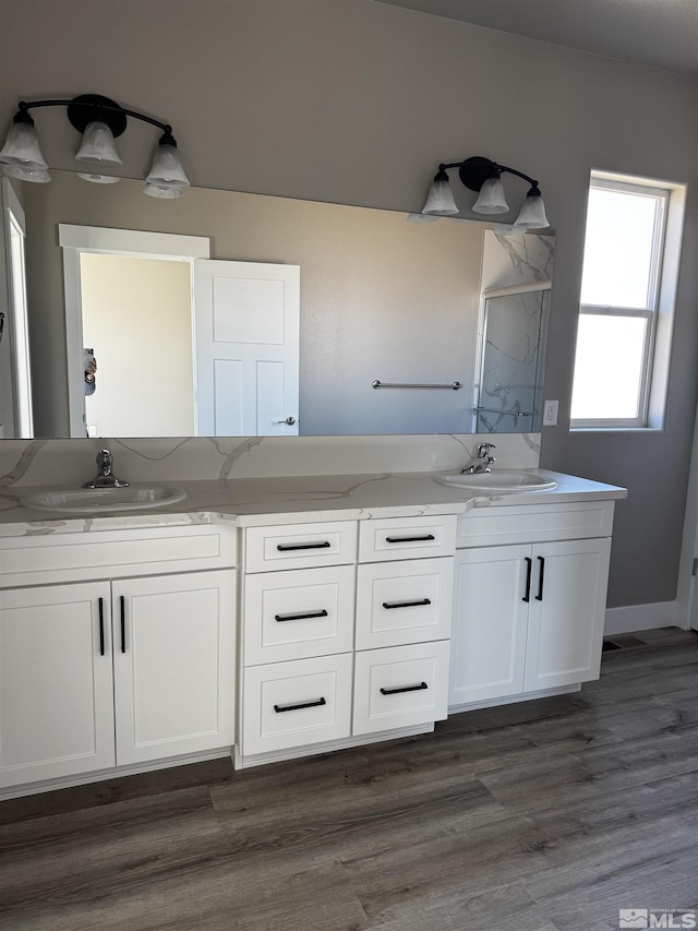 bathroom featuring double vanity, wood finished floors, and a sink