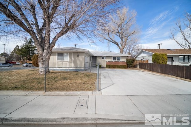 ranch-style house featuring driveway and a fenced front yard