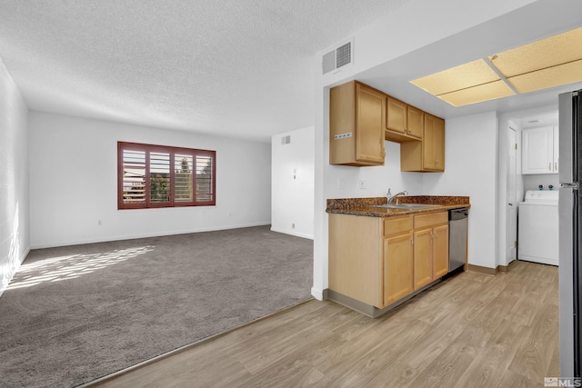 kitchen featuring a sink, open floor plan, dishwasher, washer / clothes dryer, and dark countertops