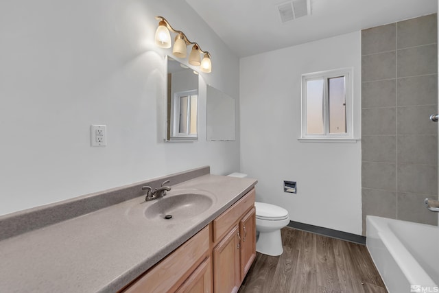 full bath with toilet, wood finished floors, vanity, and visible vents