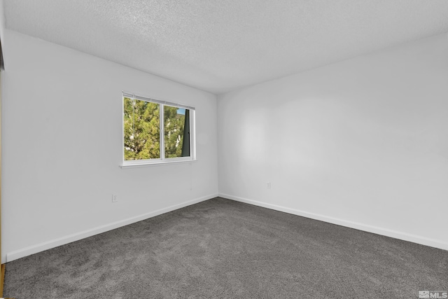 empty room with baseboards, dark colored carpet, and a textured ceiling