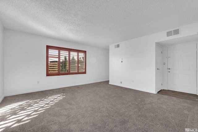 unfurnished room featuring dark carpet, visible vents, and baseboards