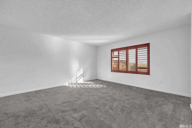 spare room featuring a textured ceiling, dark carpet, and baseboards