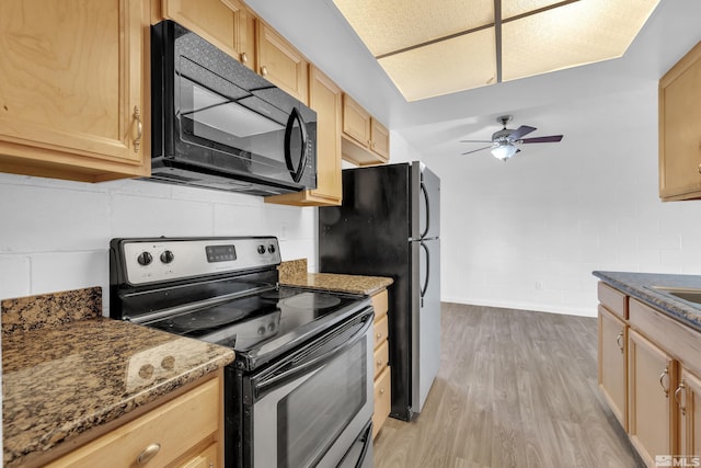 kitchen featuring light wood finished floors, stainless steel appliances, light brown cabinetry, ceiling fan, and dark stone countertops