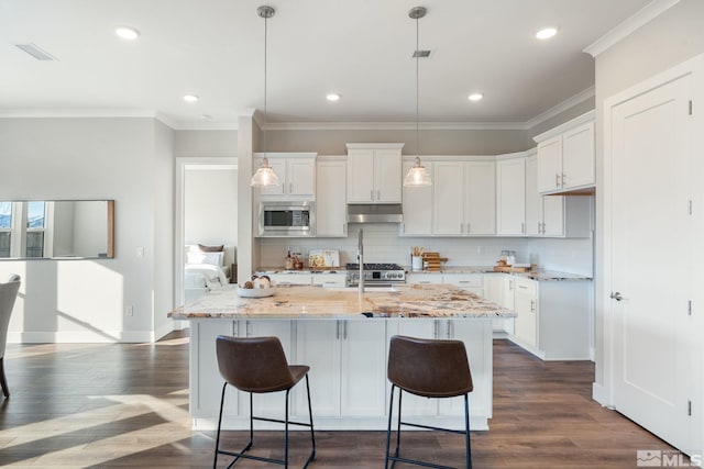 kitchen featuring under cabinet range hood, a center island with sink, appliances with stainless steel finishes, and white cabinets