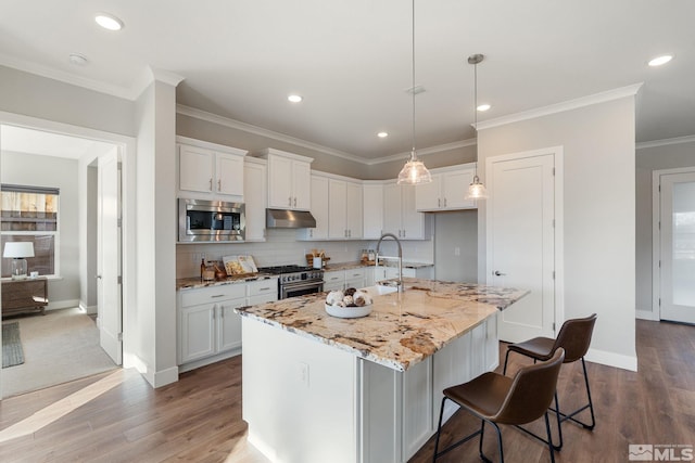 kitchen featuring stainless steel appliances, white cabinetry, and an island with sink