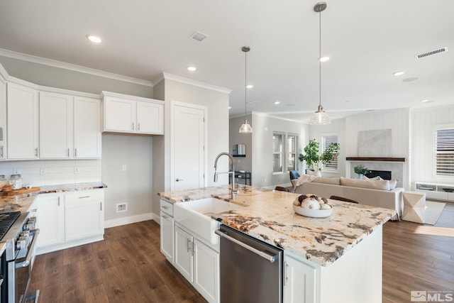 kitchen with appliances with stainless steel finishes, a center island with sink, and white cabinetry