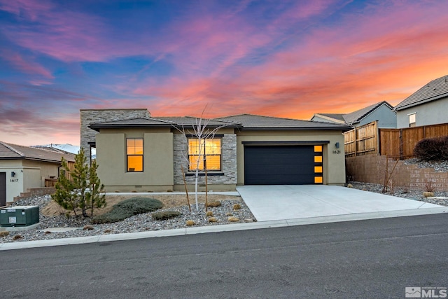 view of front of property featuring a garage, fence, concrete driveway, stone siding, and stucco siding