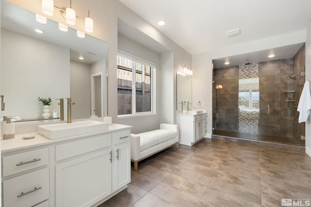 full bathroom with a stall shower, two vanities, a sink, and recessed lighting