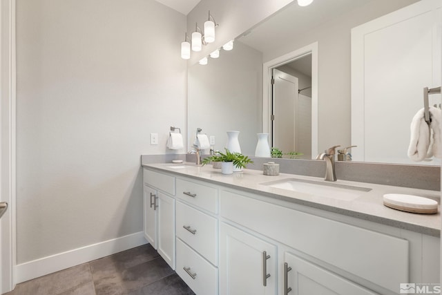 bathroom featuring tile patterned floors, a sink, baseboards, and double vanity