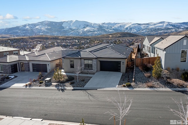 view of front of home with driveway, a residential view, an attached garage, fence, and a mountain view