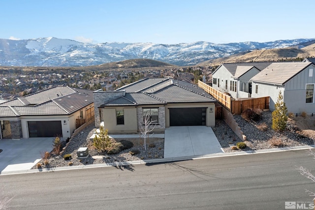 view of front of house featuring an attached garage, a mountain view, concrete driveway, a tiled roof, and a residential view