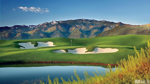 view of community featuring a lawn, golf course view, and a water and mountain view