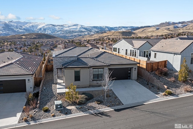 view of front of house featuring an attached garage, a mountain view, a tile roof, concrete driveway, and a residential view