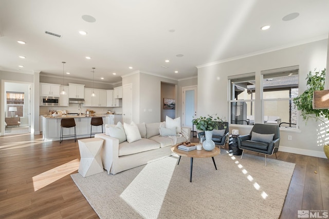 living area with recessed lighting, visible vents, baseboards, ornamental molding, and dark wood-style floors