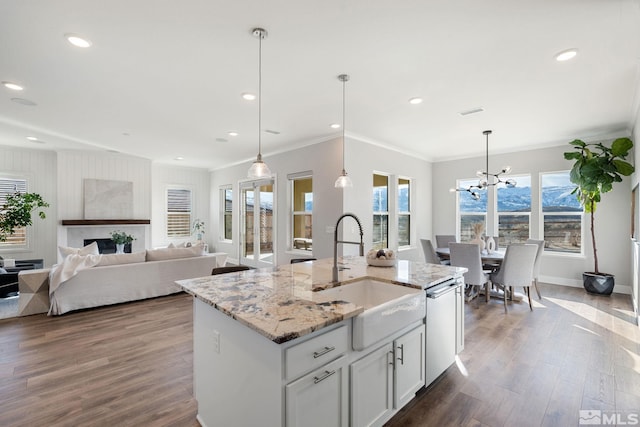 kitchen featuring pendant lighting, white cabinetry, a center island with sink, and a sink