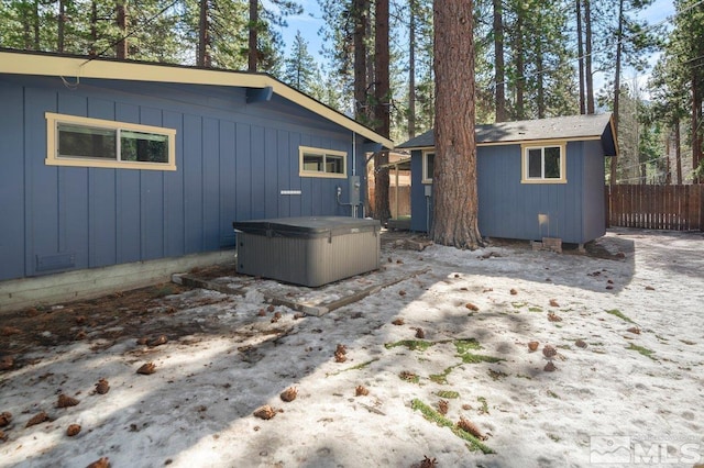 back of property featuring an outbuilding, fence, and a hot tub